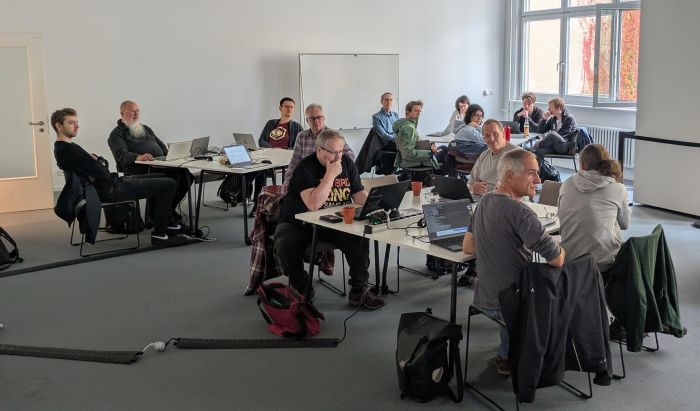 A bunch of participants with laptops sitting around large tables.